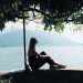 woman sitting on balustrade near body of water