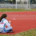Young girl resting by a running track on a sunny day. Capturing a moment of reflection.